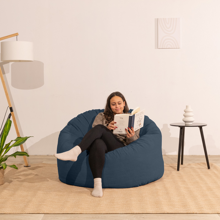 Femme assise sur un pouf en velours côtelé épais bleu foncé
