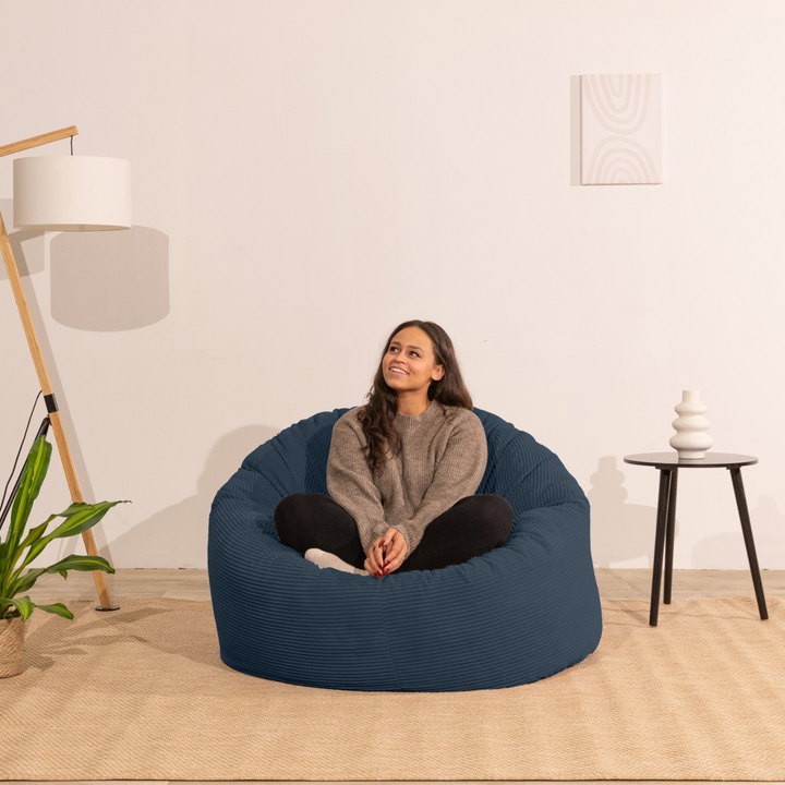 Femme assise sur un pouf en velours côtelé épais bleu foncé
