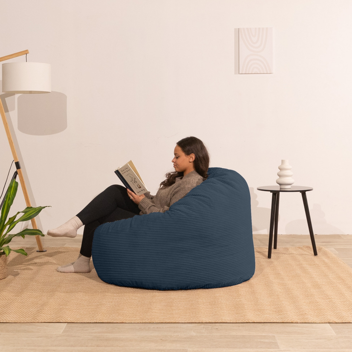 Femme assise sur un pouf en velours côtelé épais bleu foncé