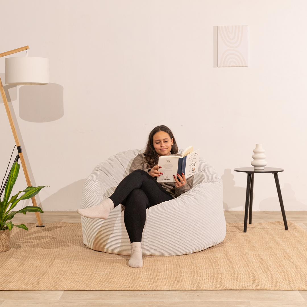 Femme assise sur un pouf en velours côtelé blanc, assise arrondie et moelleuse