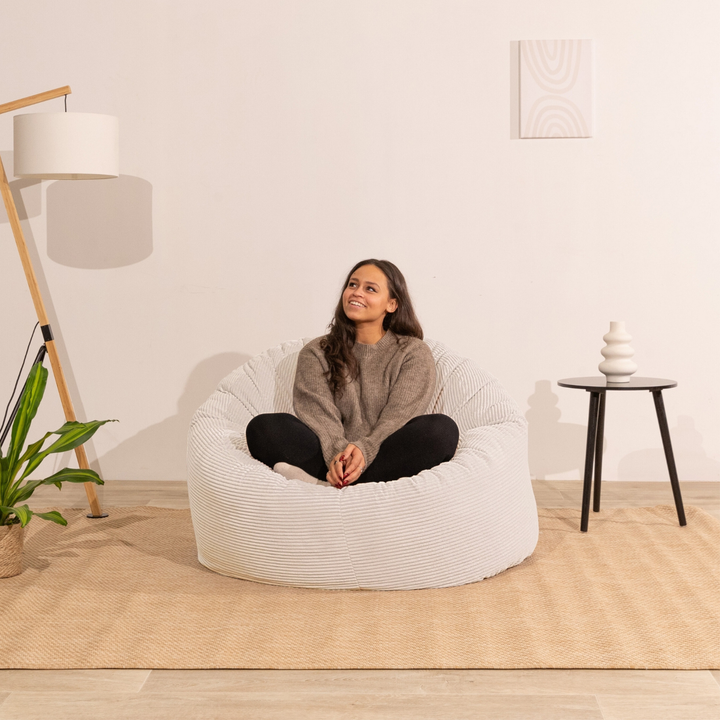 Femme assise sur un pouf en velours côtelé blanc, assise arrondie et moelleuse