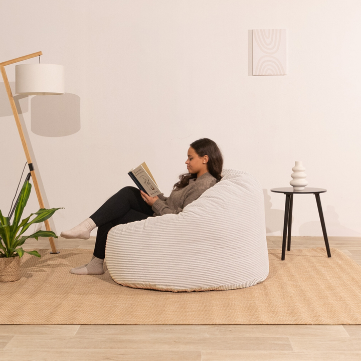Femme assise sur un pouf en velours côtelé blanc, assise arrondie et moelleuse