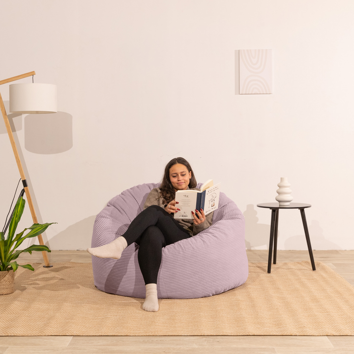 Femme assise sur un pouf en velours côtelé épais 100 cm, violet clair