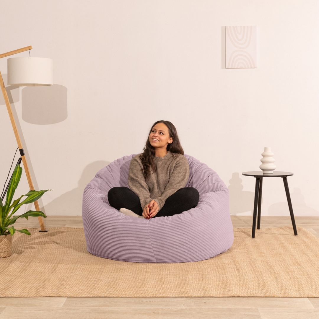 Femme assise sur un pouf en velours côtelé épais 100 cm, violet clair