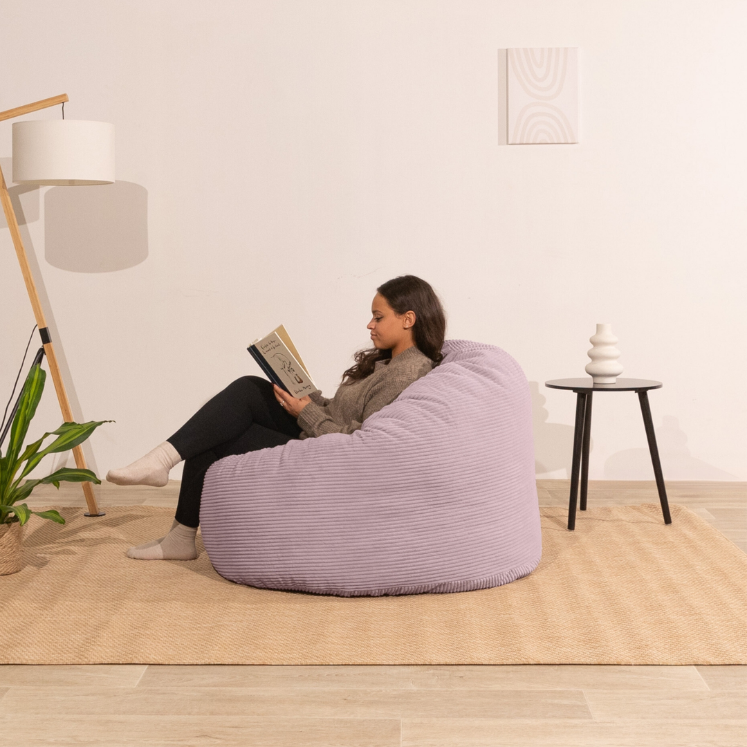 Femme assise sur un pouf en velours côtelé épais 100 cm, violet clair
