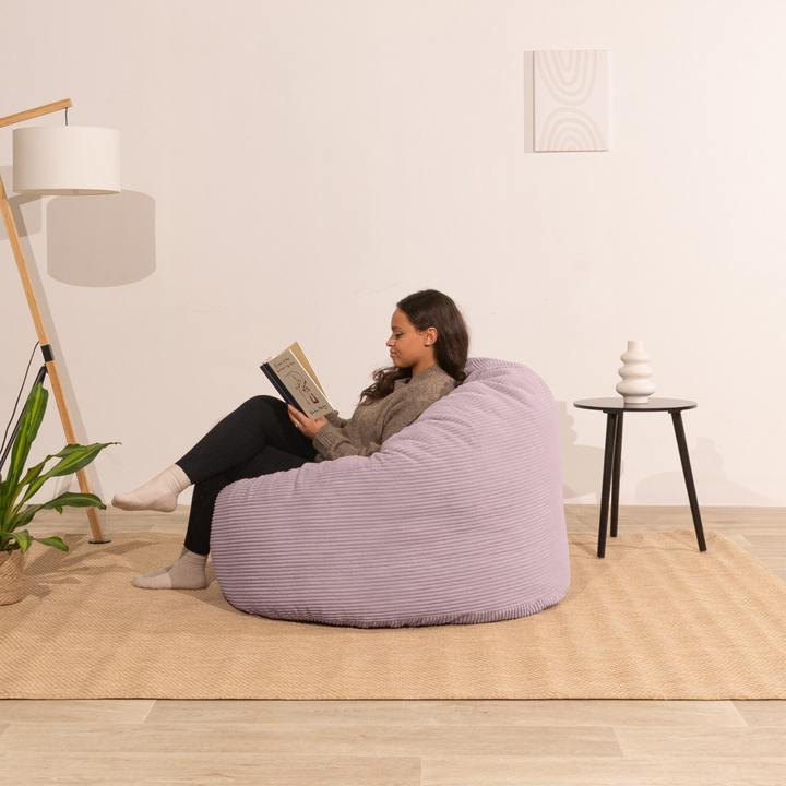 Femme assise sur un pouf en velours côtelé épais 100 cm, violet clair